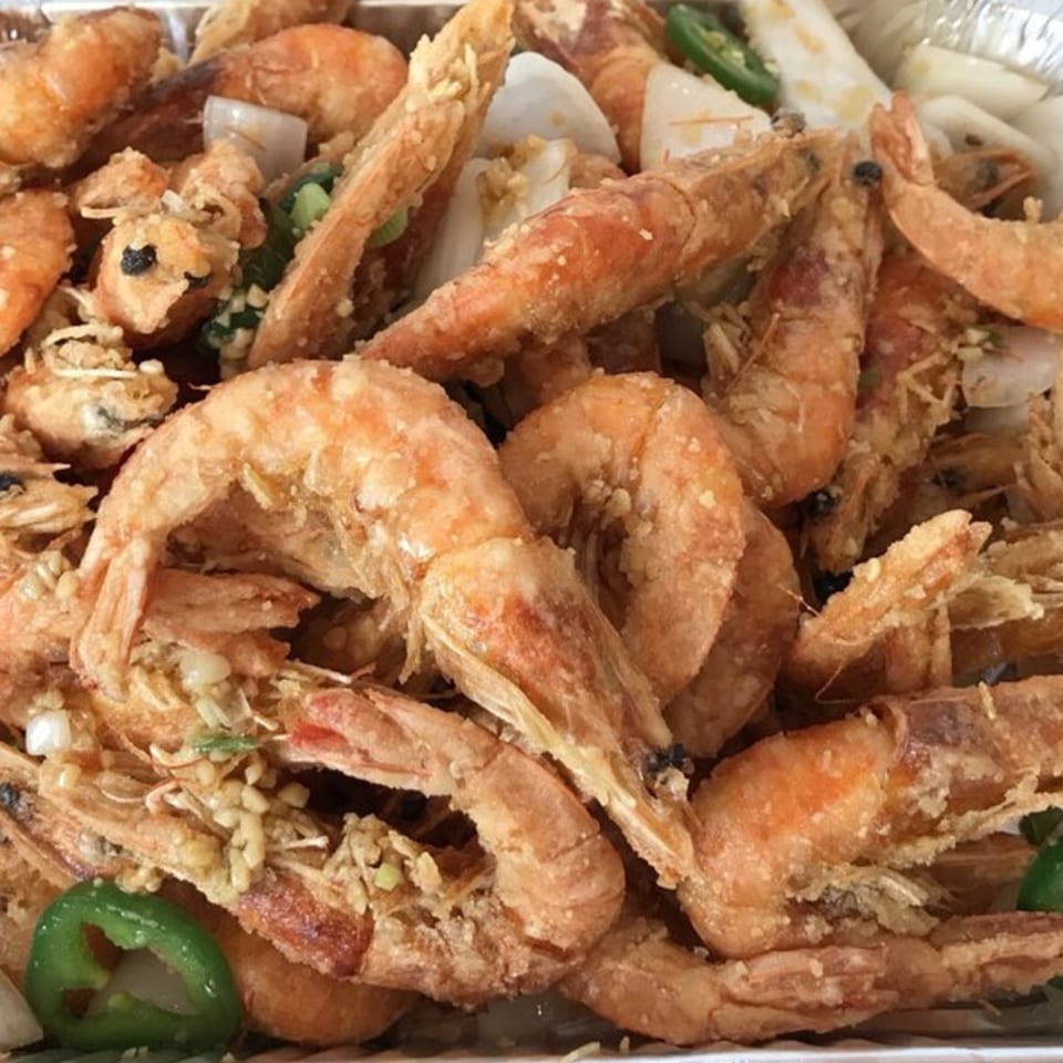 Close-up of crispy fried shrimp with garlic, onions, and green chili slices from Wong's Wok.