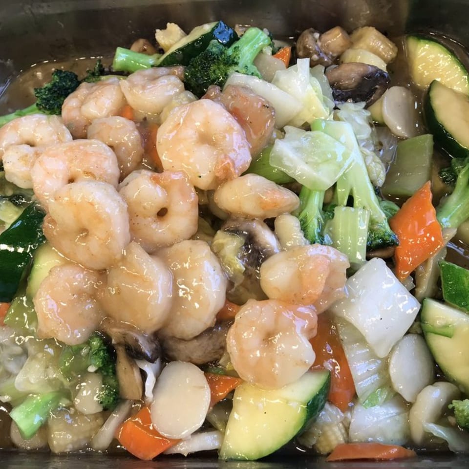 Close-up of shrimp with mixed vegetables like broccoli, carrots, and zucchini in a savory sauce.